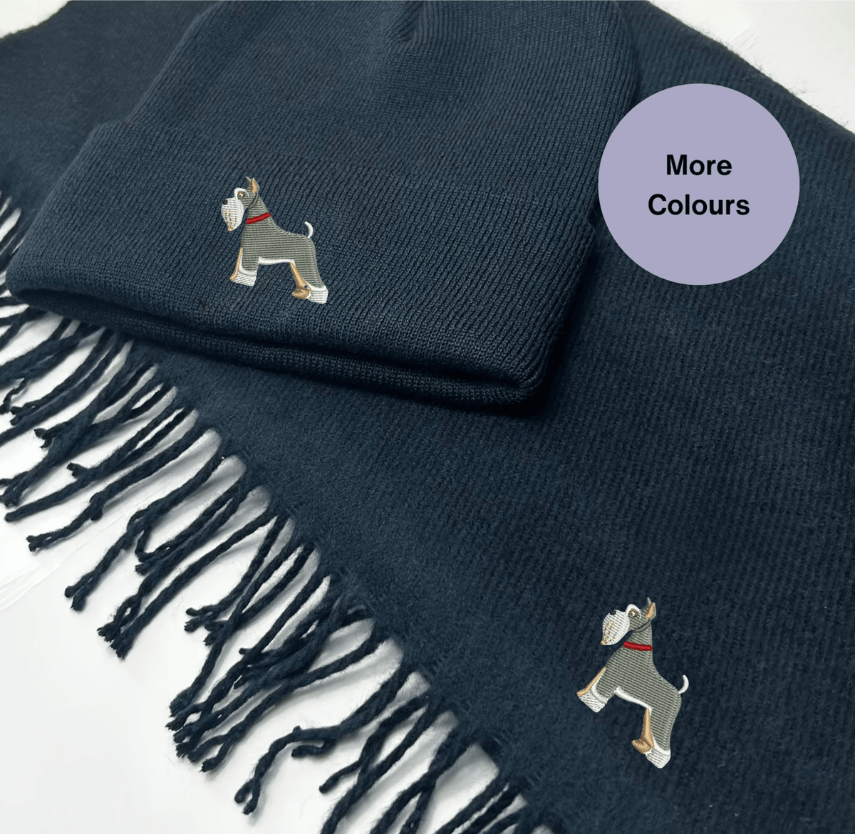 Navy knitted scarf with tassel trim and embroidered Miniature Schnauzer motifs, part of the matching hat and scarf set.