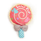Toy with a pink lollipop design and polka dot bow on a white background