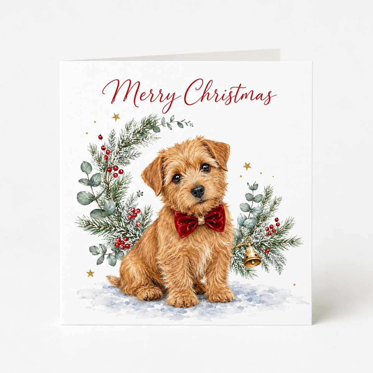 A square Christmas greeting card featuring a watercolor illustration of a small Norfolk terrier wearing a red bow tie, surrounded by green holly and red berries, with 'Merry Christmas' written in red script at the top.