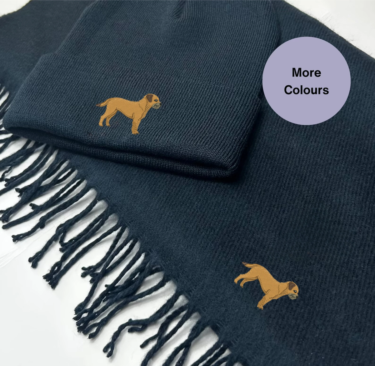 Navy beanie hat and tasselled scarf with tan Border Terrier embroidery on both pieces.